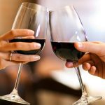 Male and female hands toasting wine glasses.